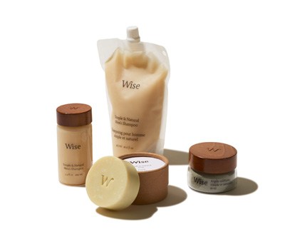 Wise men's grooming products including refillable glass containers, pomade, shampoo and soap with minimal branding and wooden caps.