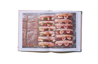 Open cookbook showing colorful food photography of prepared dishes and breads.