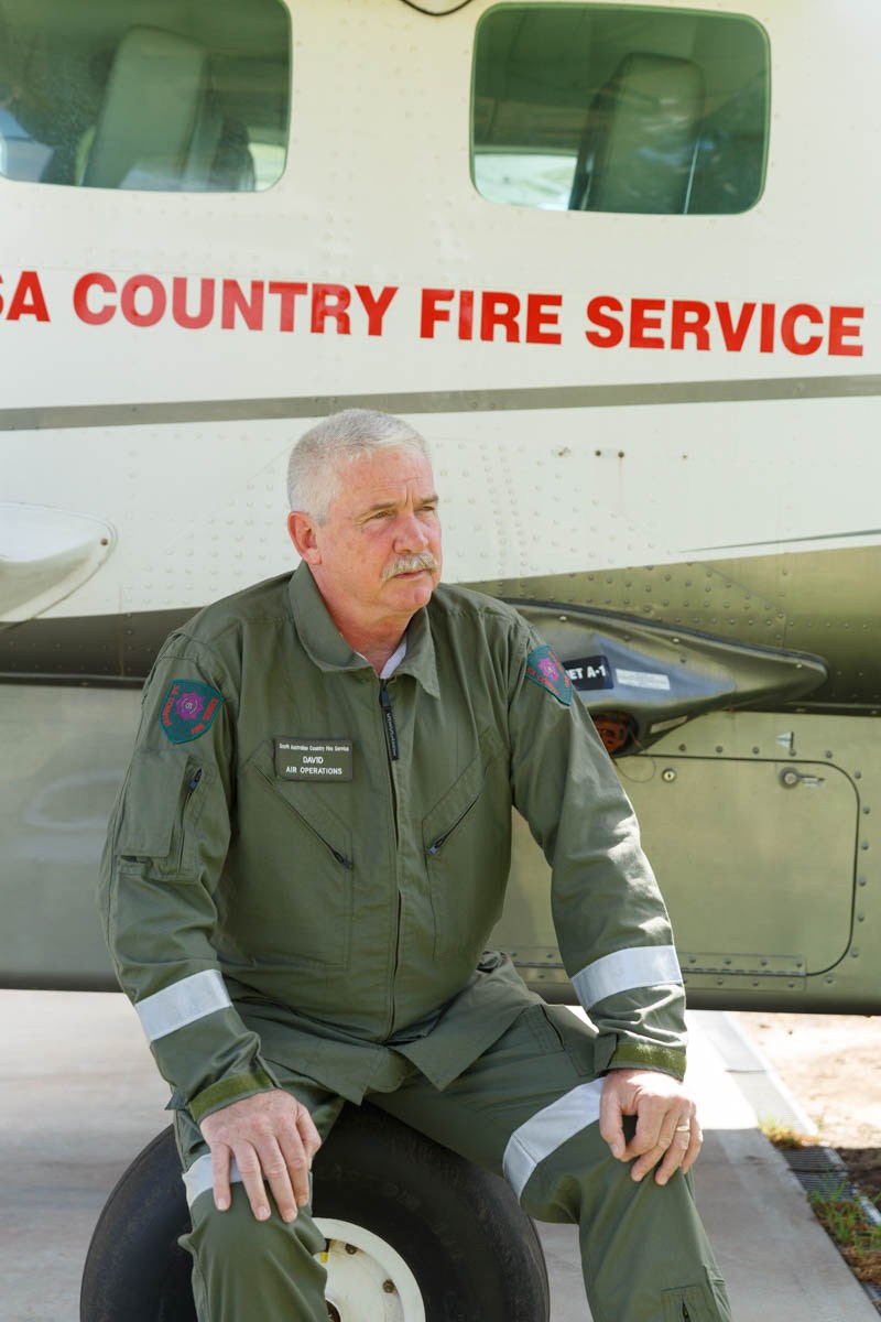 Commander David Pearce in flight suit sitting in front of a South Australian Country Fire Service aircraft.