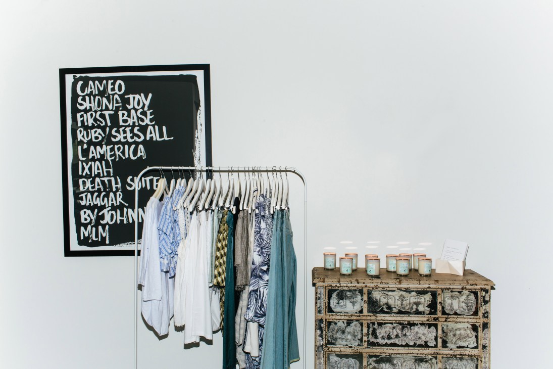 Interior of A Little Birdie Told Me boutique with clothing rack and vintage chest displaying candles