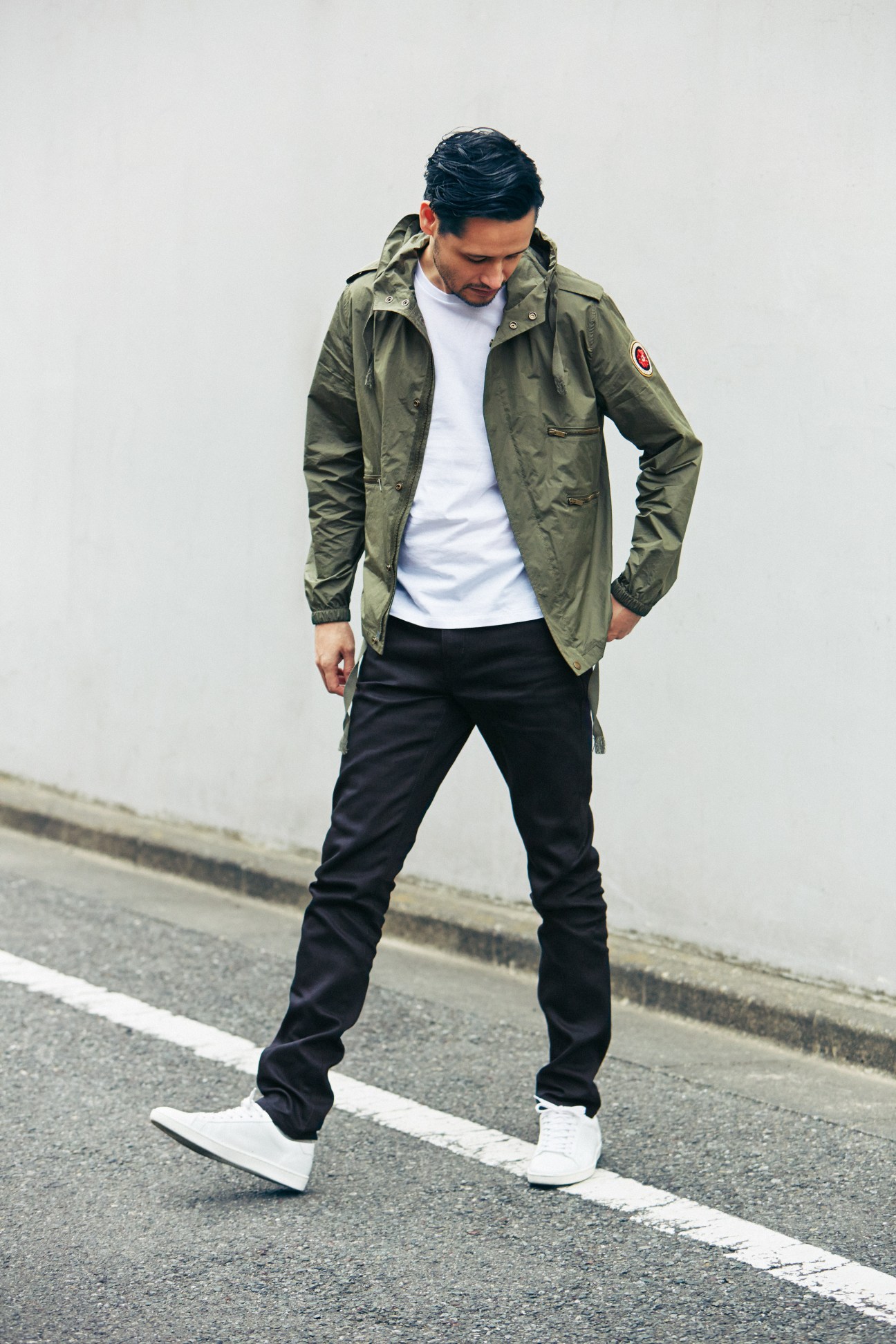 Man wearing Saint Laurent jacket, t-shirt and jeans standing on pavement.