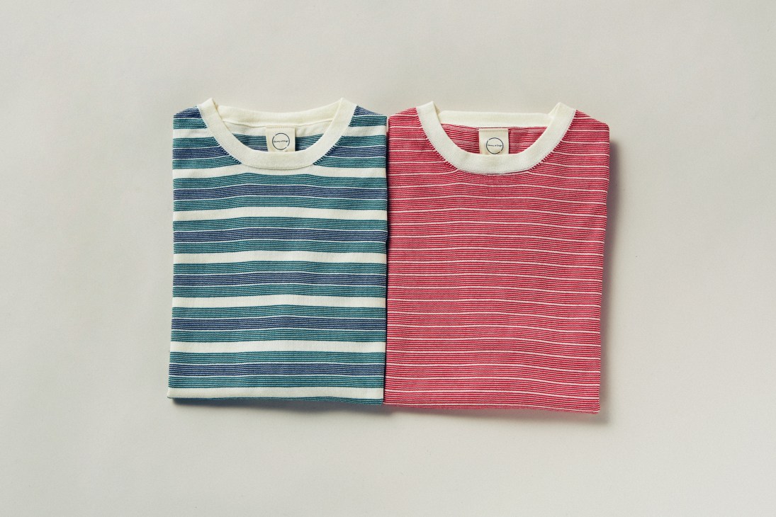 Two striped short-sleeved jumpers in blue and red colorways with cream neckbands displayed on white background.