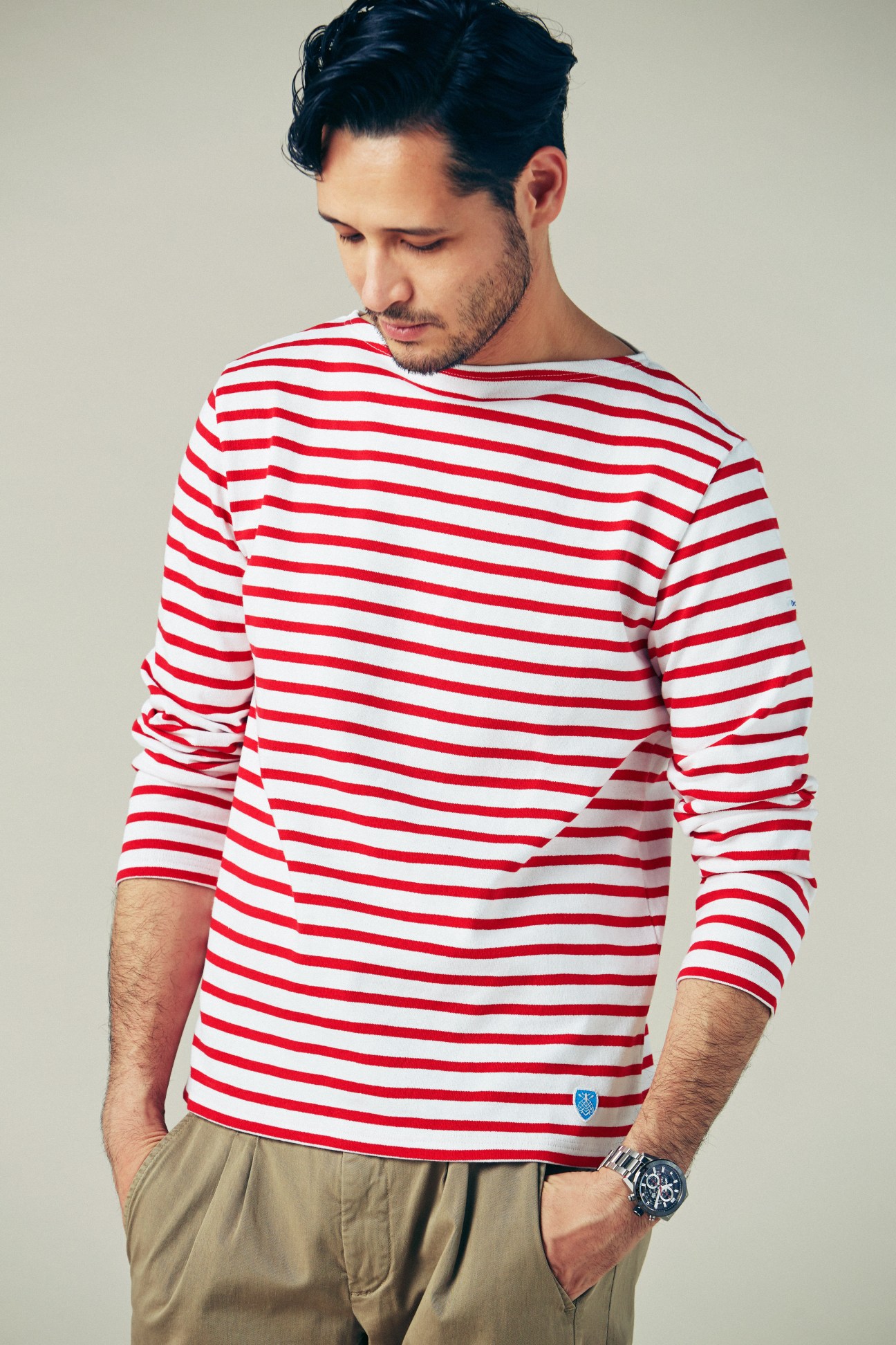 Man wearing red and white striped long-sleeve shirt with tan trousers and a watch.