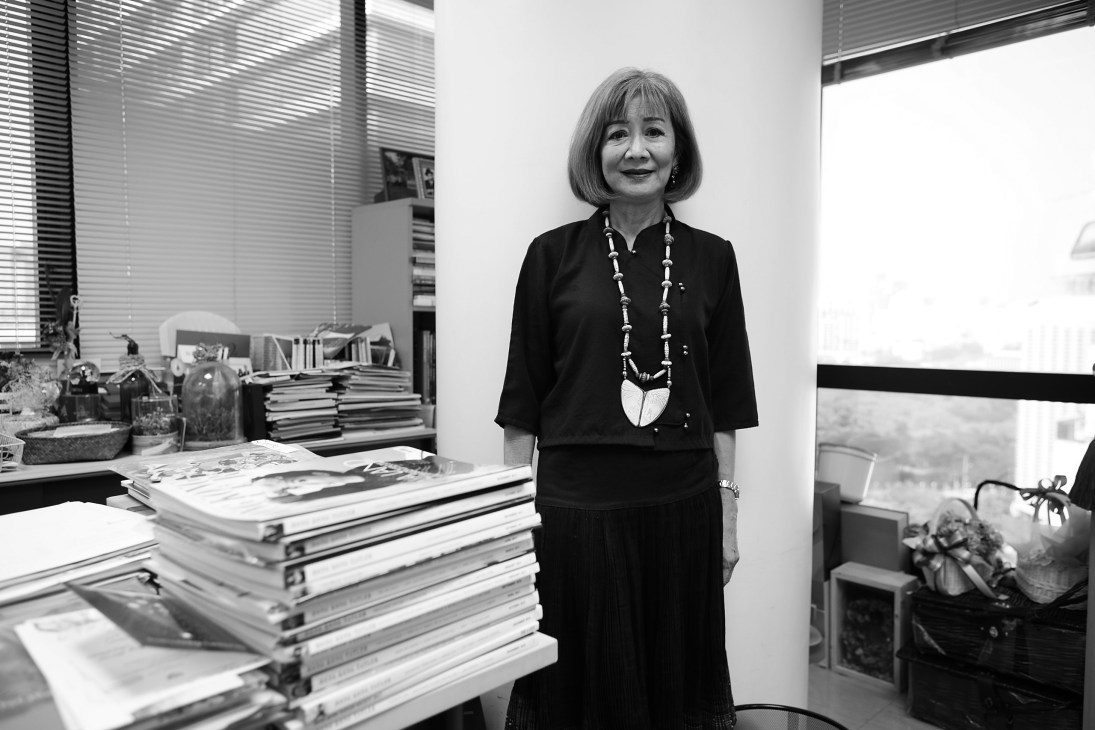 Naphalai Areesorn, editor-in-chief of Thailand Tatler, stands in her office beside stacks of magazines.