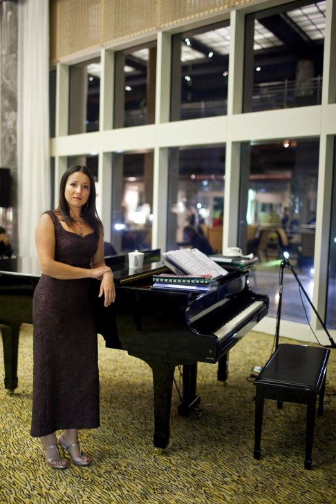 Svetlana Moreva, pianist, poses beside a grand piano in Le Royal Méridien hotel lobby in Abu Dhabi.
