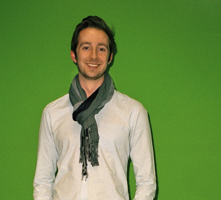 Alex Morgan, presenter of The Cube, smiles at the camera against a green background.