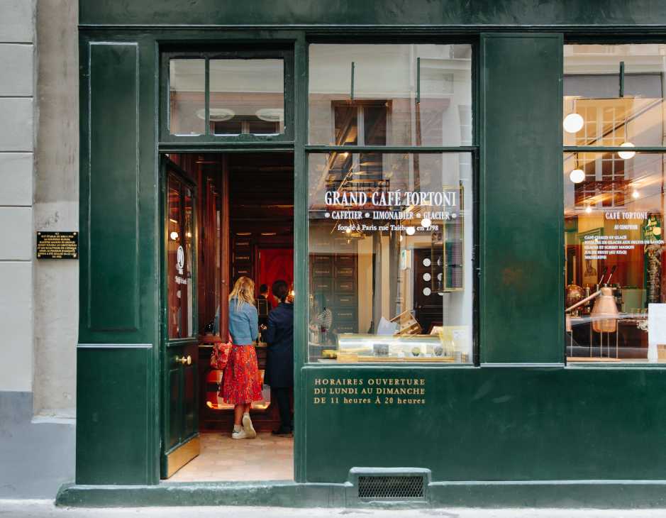 Grand Café Tortoni storefront with bottle-green shopfront and window displays in Paris Le Marais.