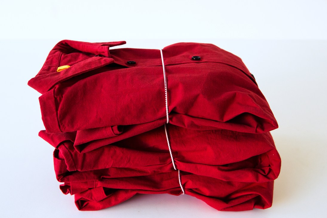 Folded red padded down vest with black buttons and yellow interior lining detail.