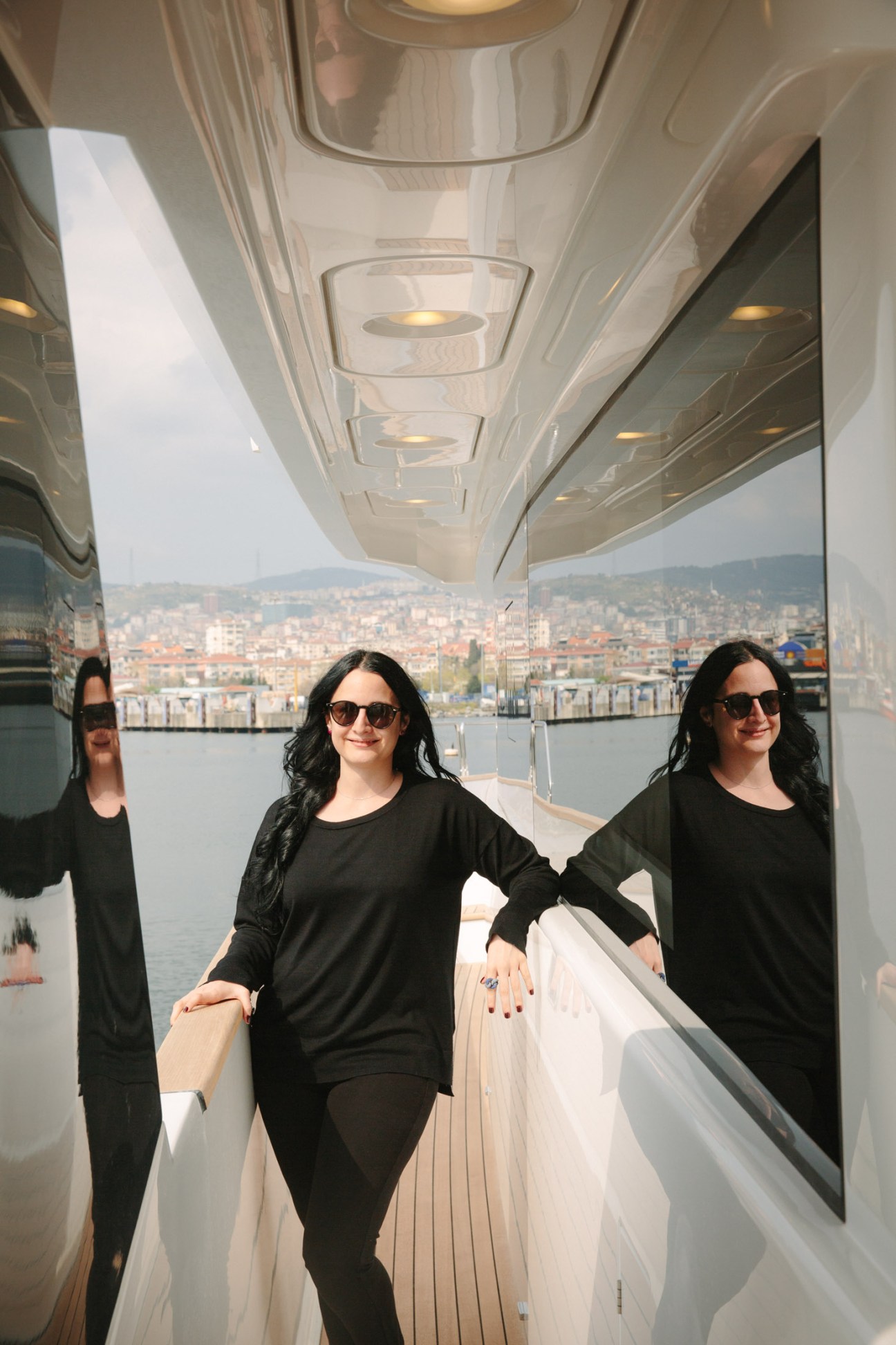 Ipek Kirac stands on the deck of a Sirena Marine powerboat with a coastal city visible across the water.