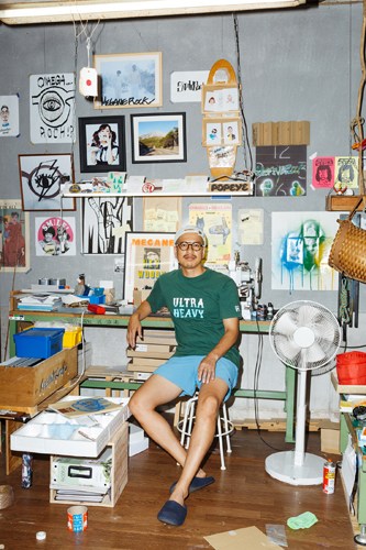Daisuke Amada in his eyewear workshop surrounded by frames and design materials.