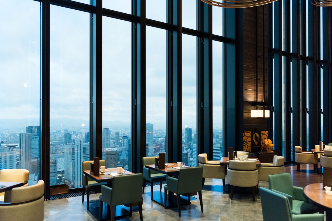 High-altitude restaurant with floor-to-ceiling windows overlooking a river and cityscape at Conrad Osaka.