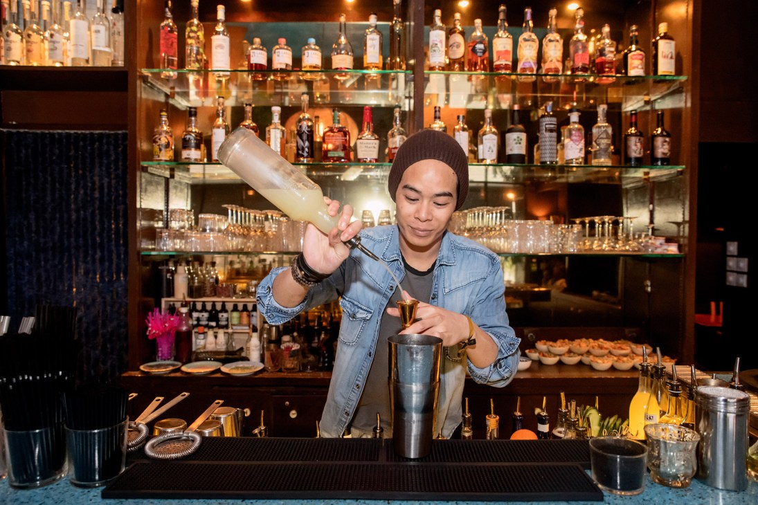 Bartender mixing a cocktail at Gaspard, a modern cocktail bar in Marseille, with well-stocked shelves behind.