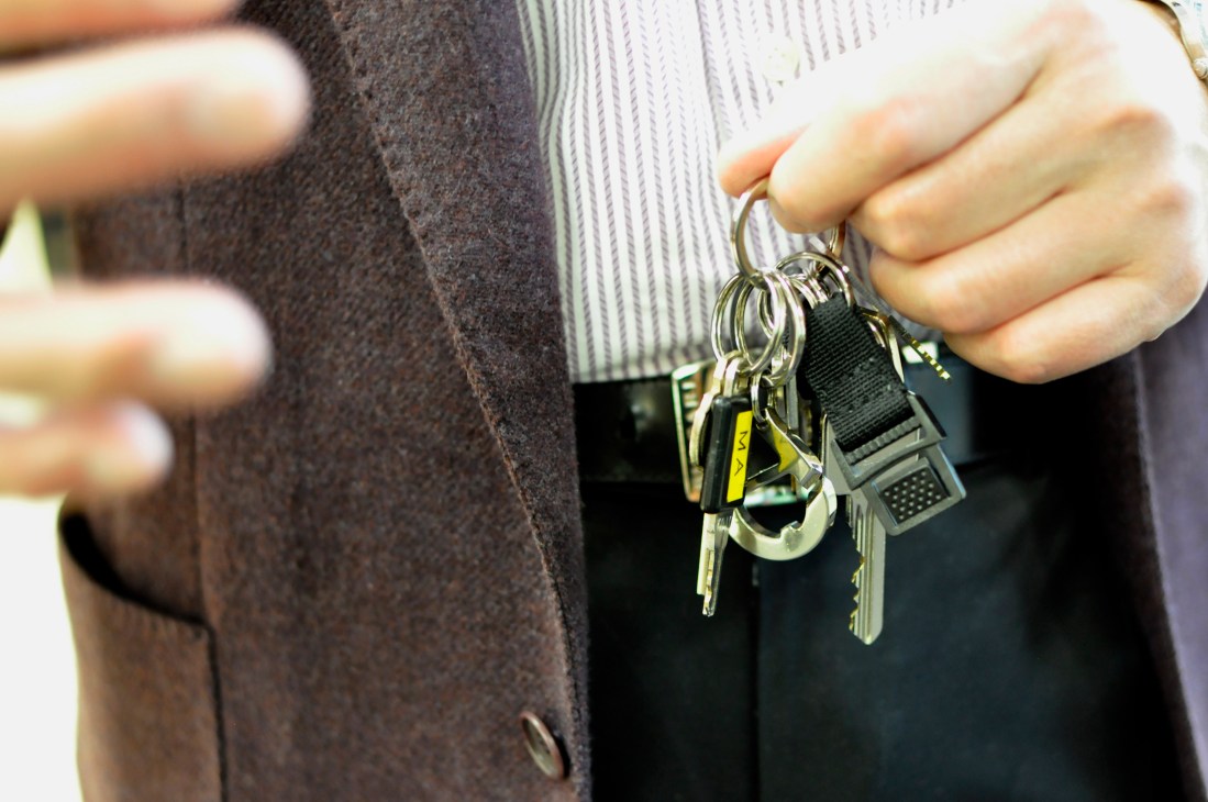 Person holding an Octopus card keychain with multiple keys while wearing business attire.