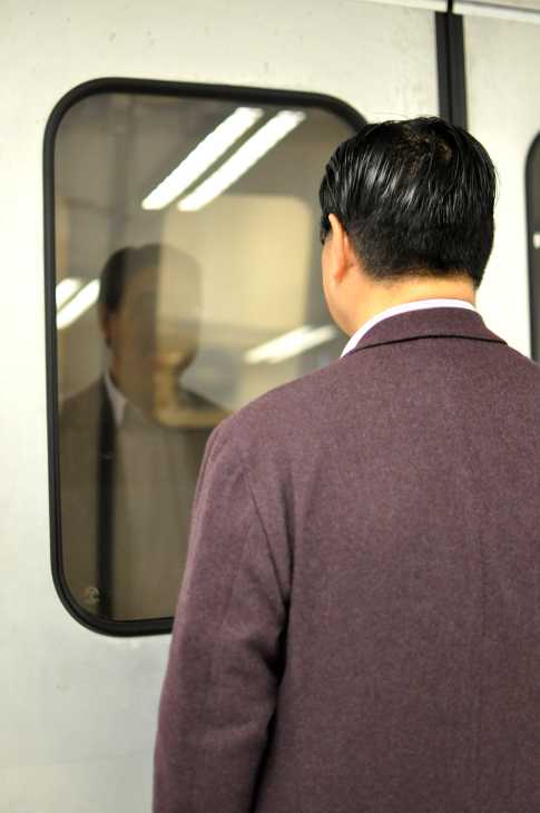 Man in burgundy sweater looking at his reflection in a mirror