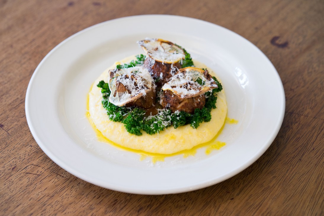 Plated dish with seared meat on creamed polenta and greens at Etto restaurant.