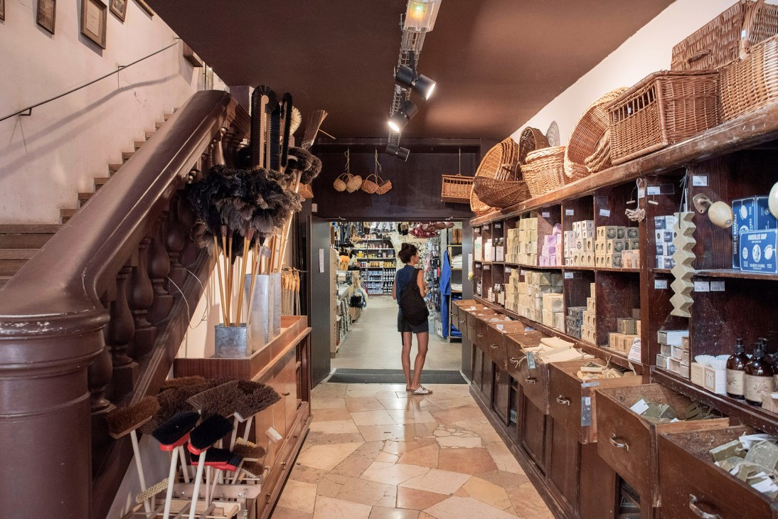 Interior of La Vielle Charité in Le Panier with stone arches, wooden display cases, wicker baskets, and a visitor browsing.