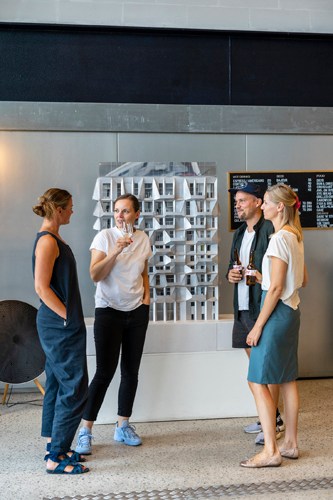 Four people stand around a white table examining an architectural model of a building at Cobe design studio in Copenhagen.