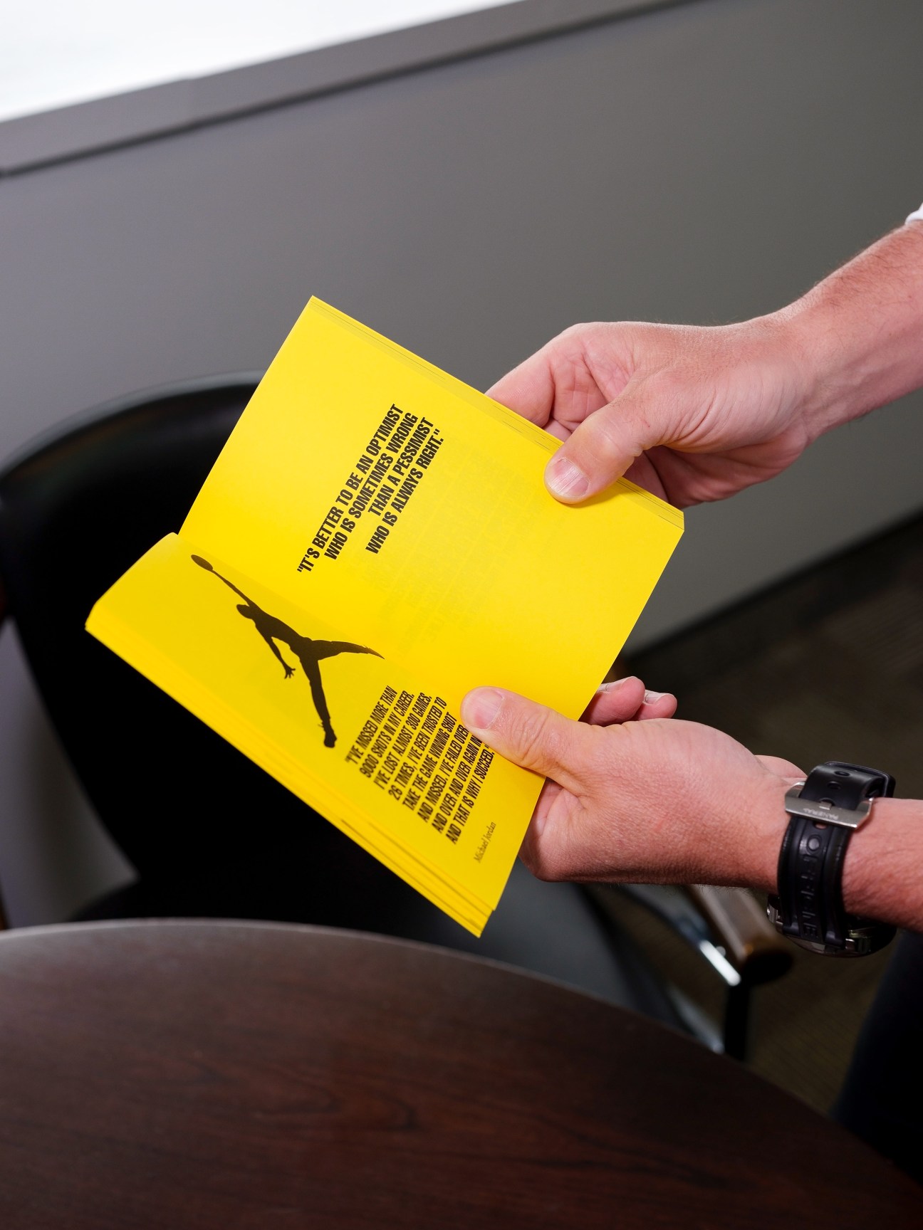 Hand holding a bright yellow book with a silhouette figure illustration and text on its cover.