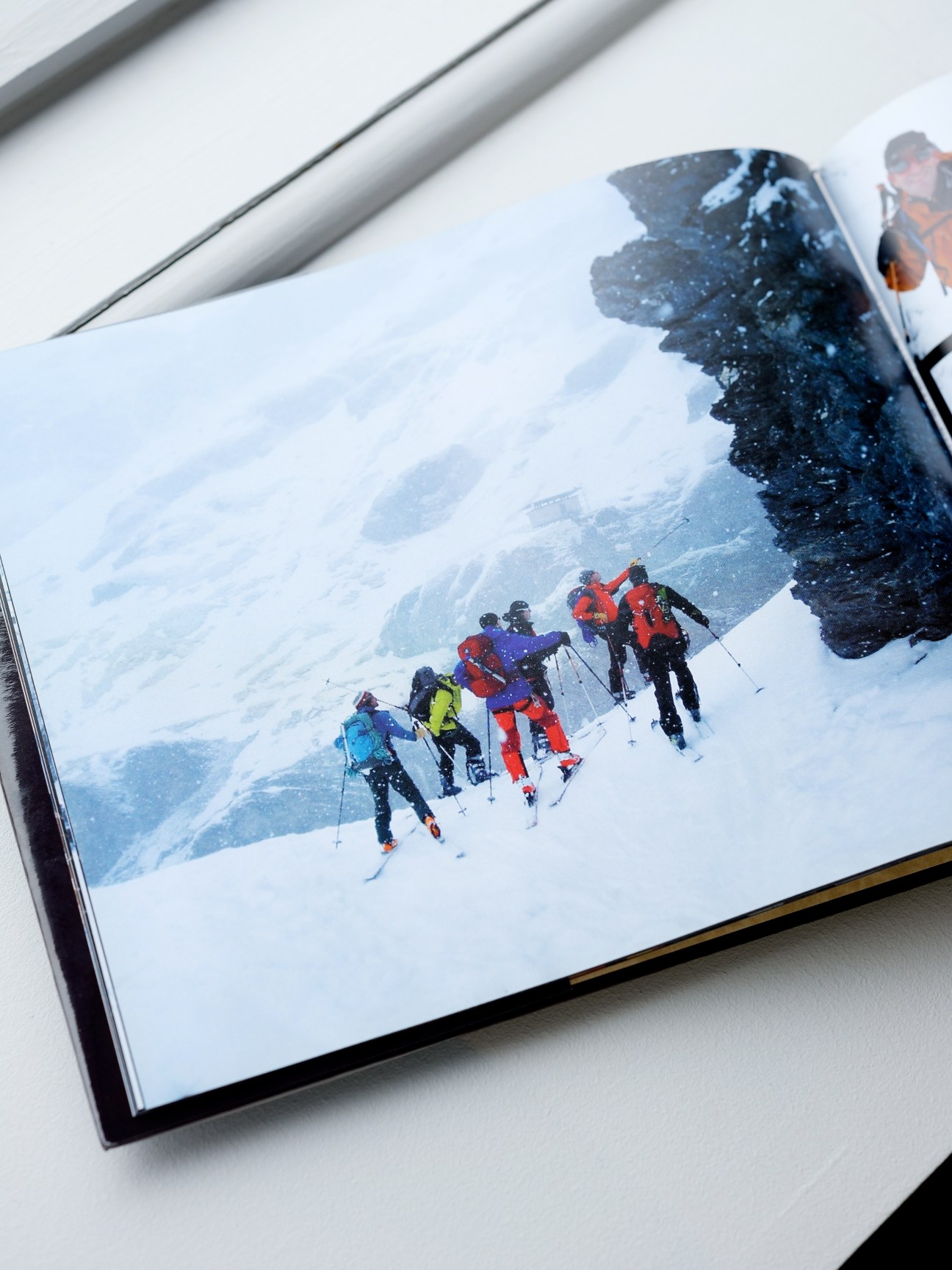 Group of skiers in colorful winter gear descending a snowy mountain slope.