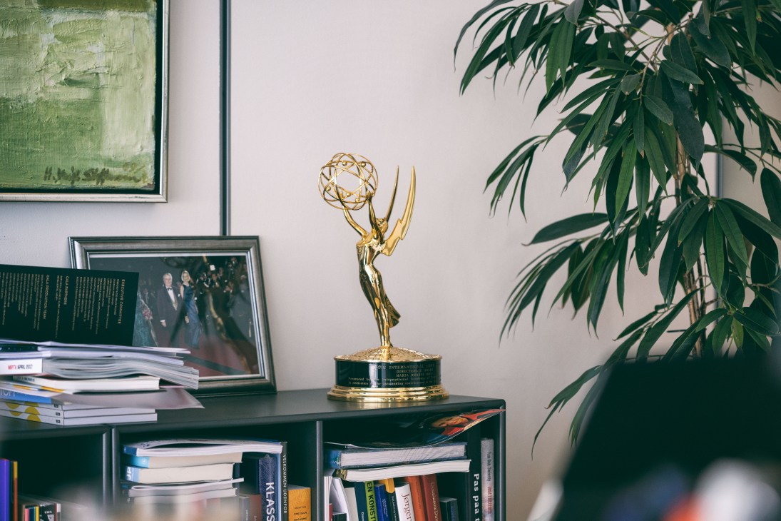An Emmy award displayed on a desk next to books and a framed photograph in an office.