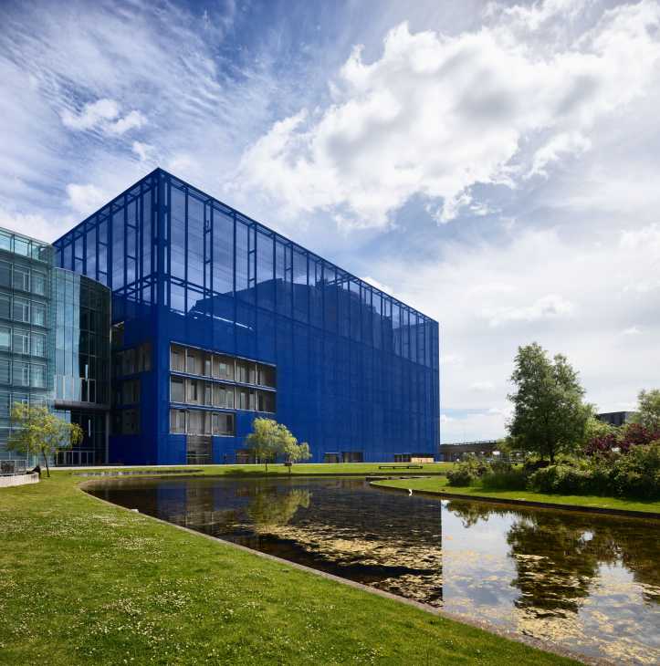 DR Koncerthuset, a modern blue-glass building with a reflecting pond and green lawn in Copenhagen.