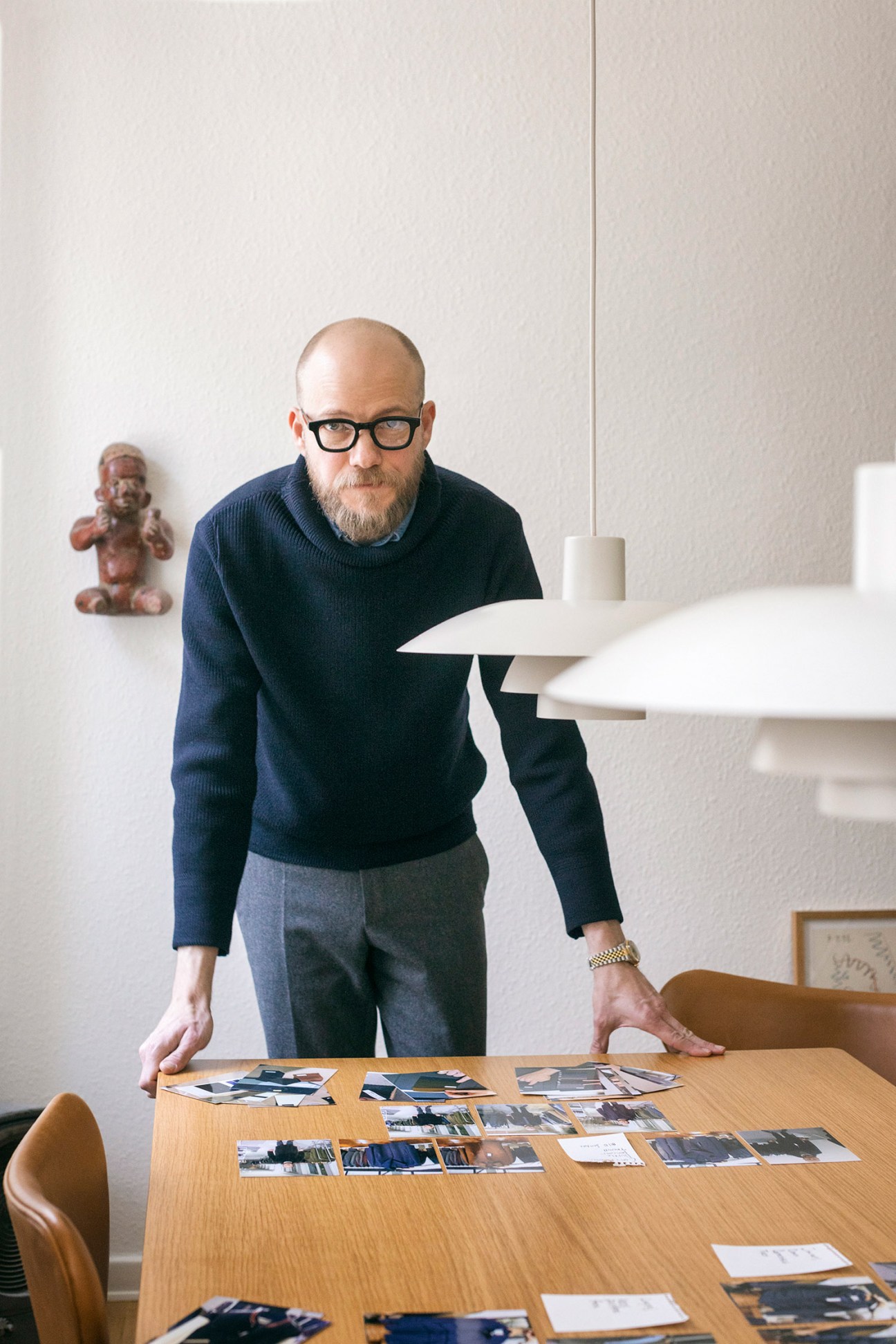 Taylor Caruso, co-founder of County Ltd, stands at a wooden table reviewing photographs and line sheet cutouts arranged in a collage.