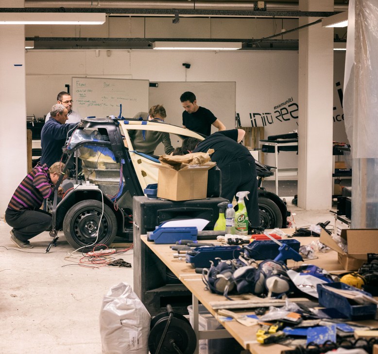 Team members work on assembling an electric vehicle prototype in a workshop.