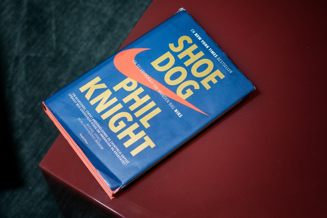 Shoe Dog book by Phil Knight on a burgundy and teal surface.