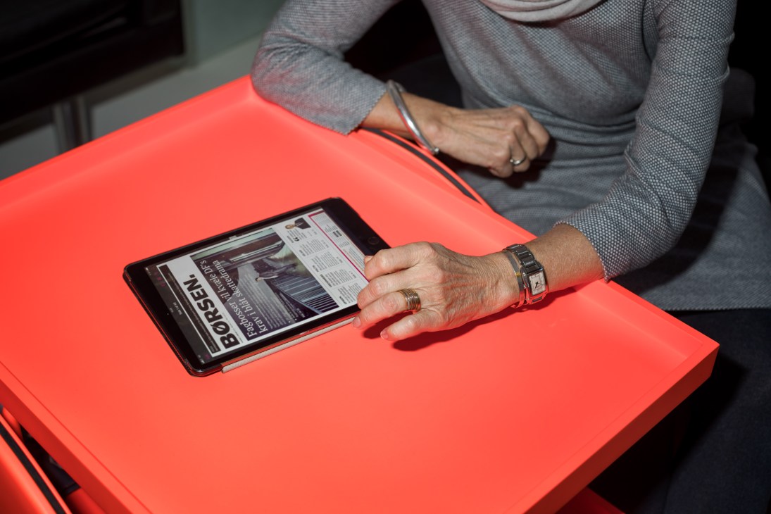 Person's hands holding an iPad displaying a Bosch website on a bright red surface.