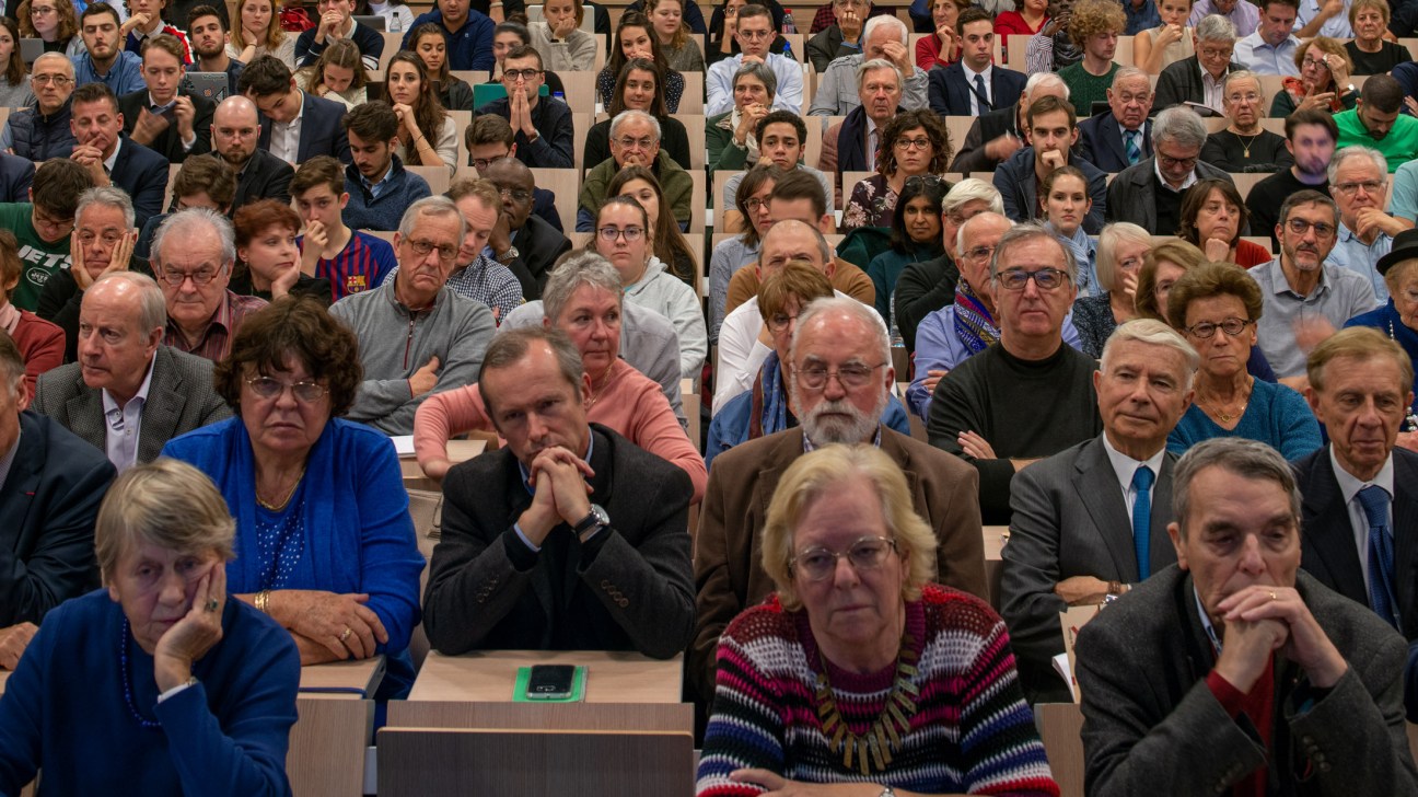 A large audience seated in a lecture hall attentively listening to a debate on the geopolitics of Russia.