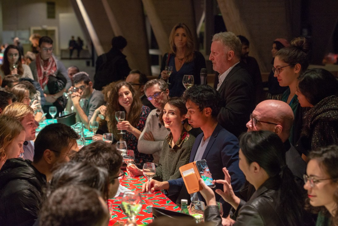 Attendees gather around a table with wine glasses at the Unesco philosophy night's In Vino Veritas session.