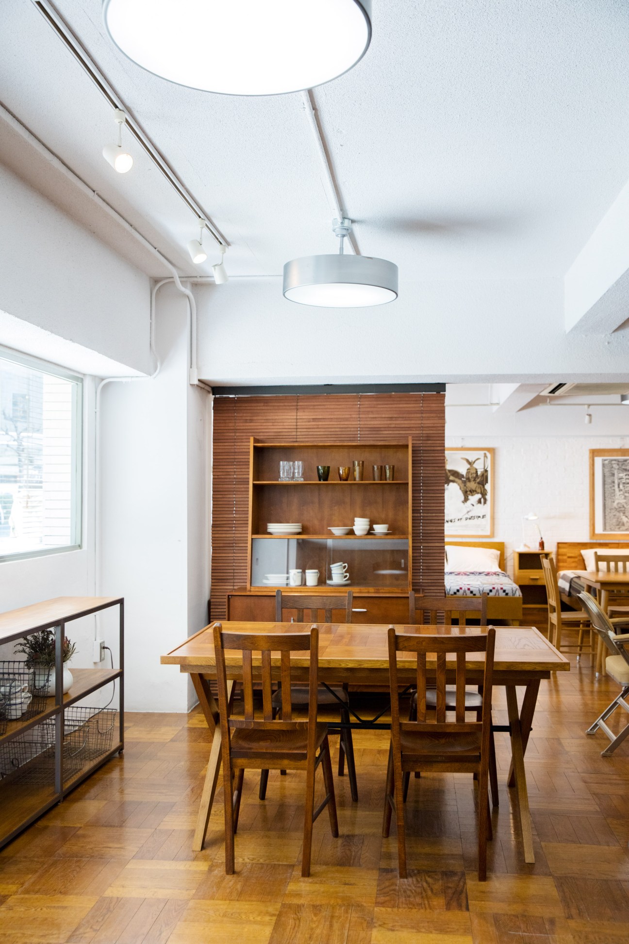 Modern dining room with wooden table, chairs, pendant light, and built-in shelving with ceramics.