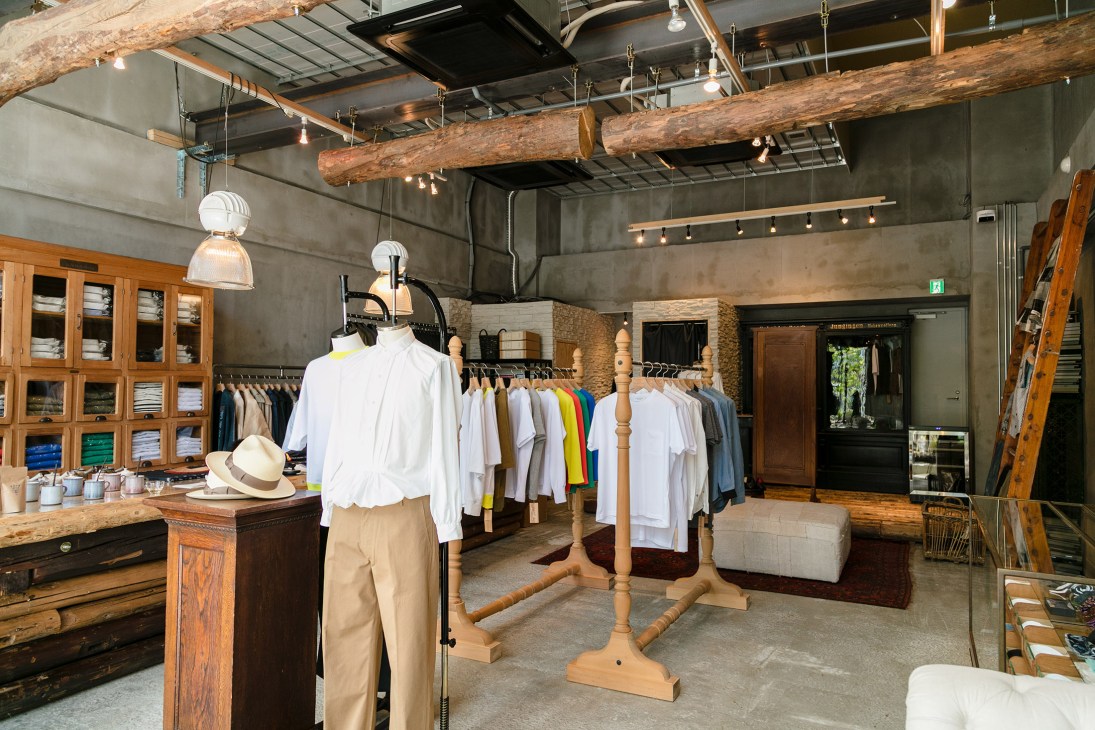 Interior of Franklin Tailored retail store in Tokyo showing wooden display racks, clothing on hangers, and industrial ceiling with exposed beams.