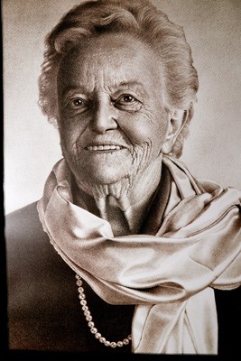 Portrait of an older woman wearing a pearl necklace and light-colored scarf.