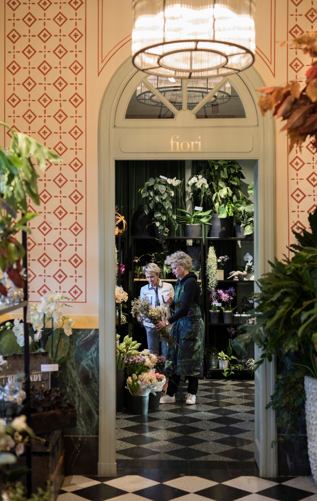 Florist shop interior with plants and flowers displayed in storefront windows.
