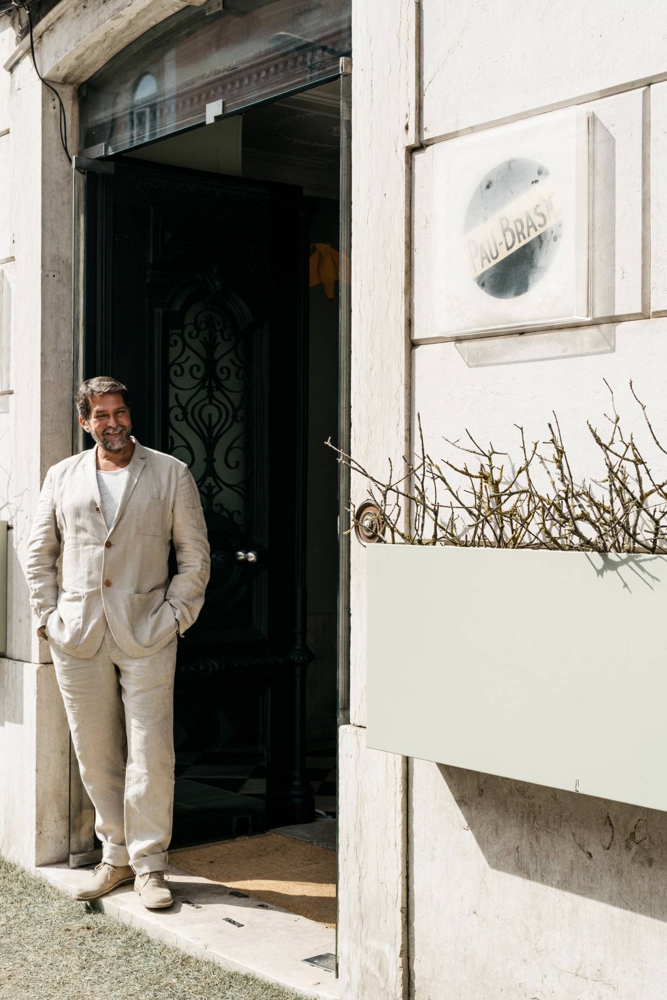 Rui Gomes Araújo stands outside Casa Pau-Brasil in Lisbon wearing a cream linen suit.