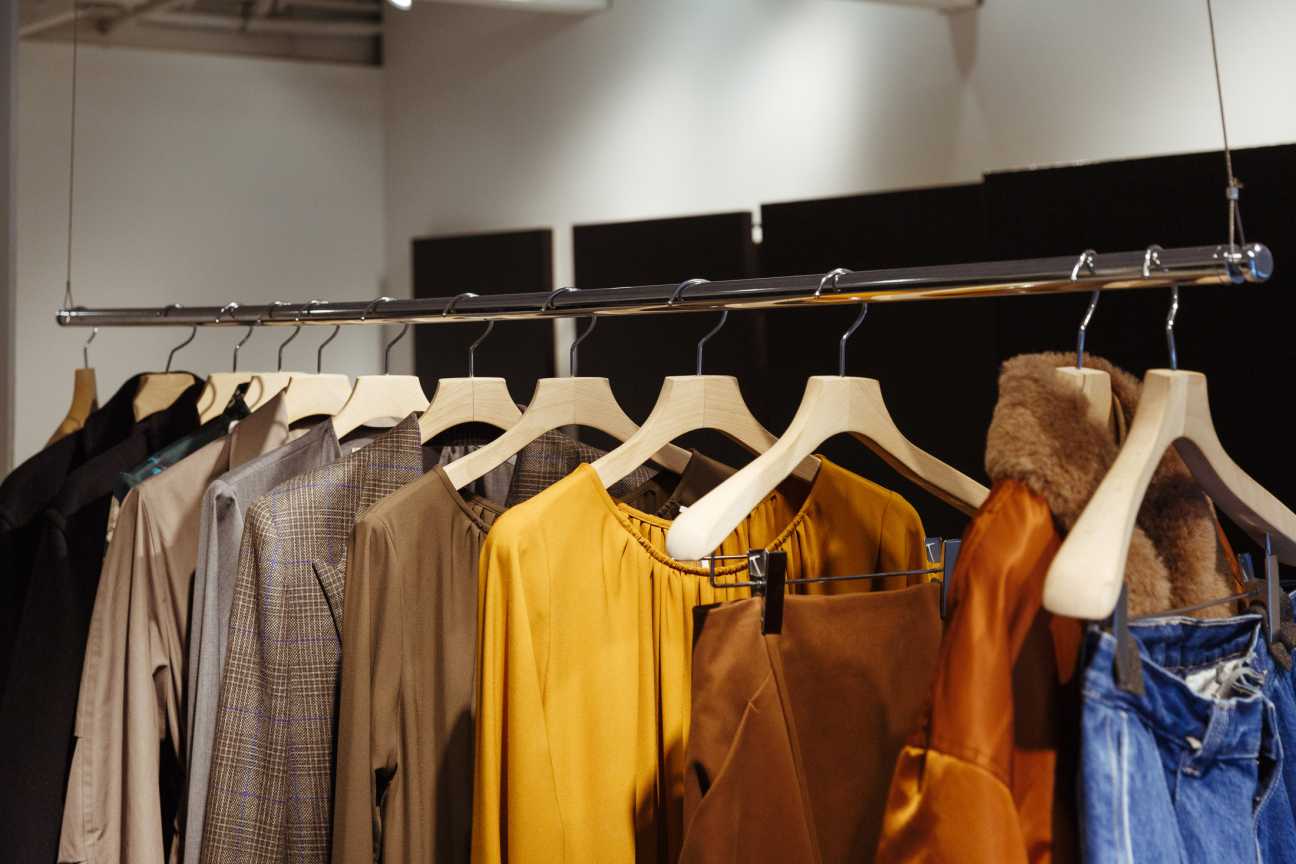 Graphpaper store interior with clothing on wooden hangers and white display shelving