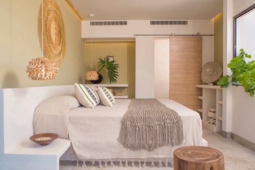 Modern hotel bedroom with neutral tones, woven wall art, and natural textures
