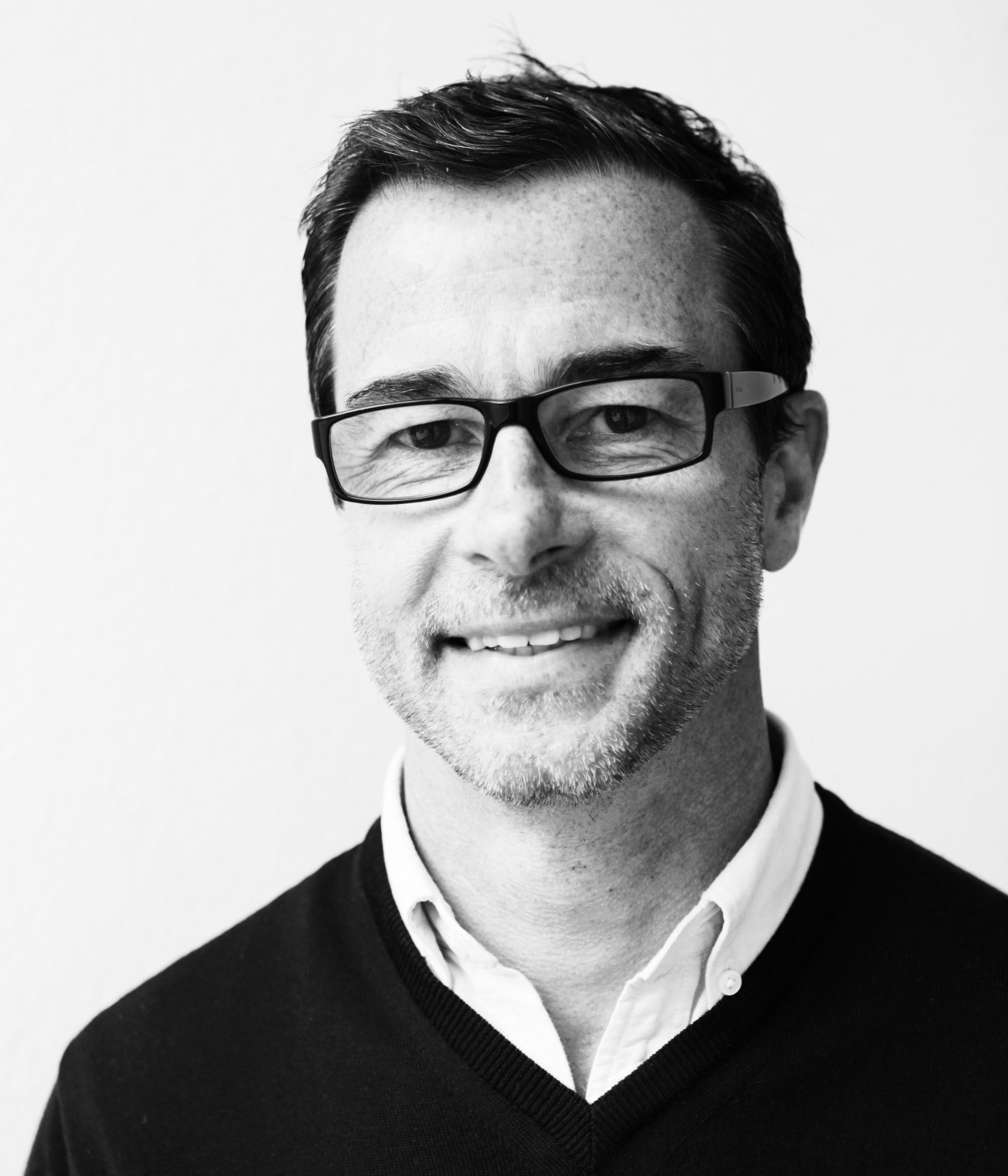 Black and white portrait of Andrew Tuck, Monocle's editor, wearing glasses and a dark sweater.