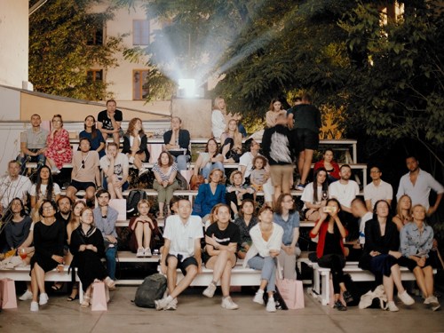 Large group of people posing together on outdoor steps at night in an urban setting.
