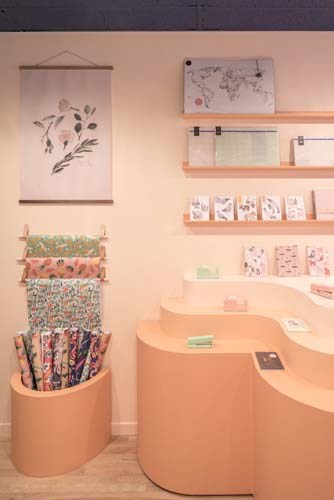 In Bed retail store interior with peach curved furniture, wooden shelving, and displayed textiles.