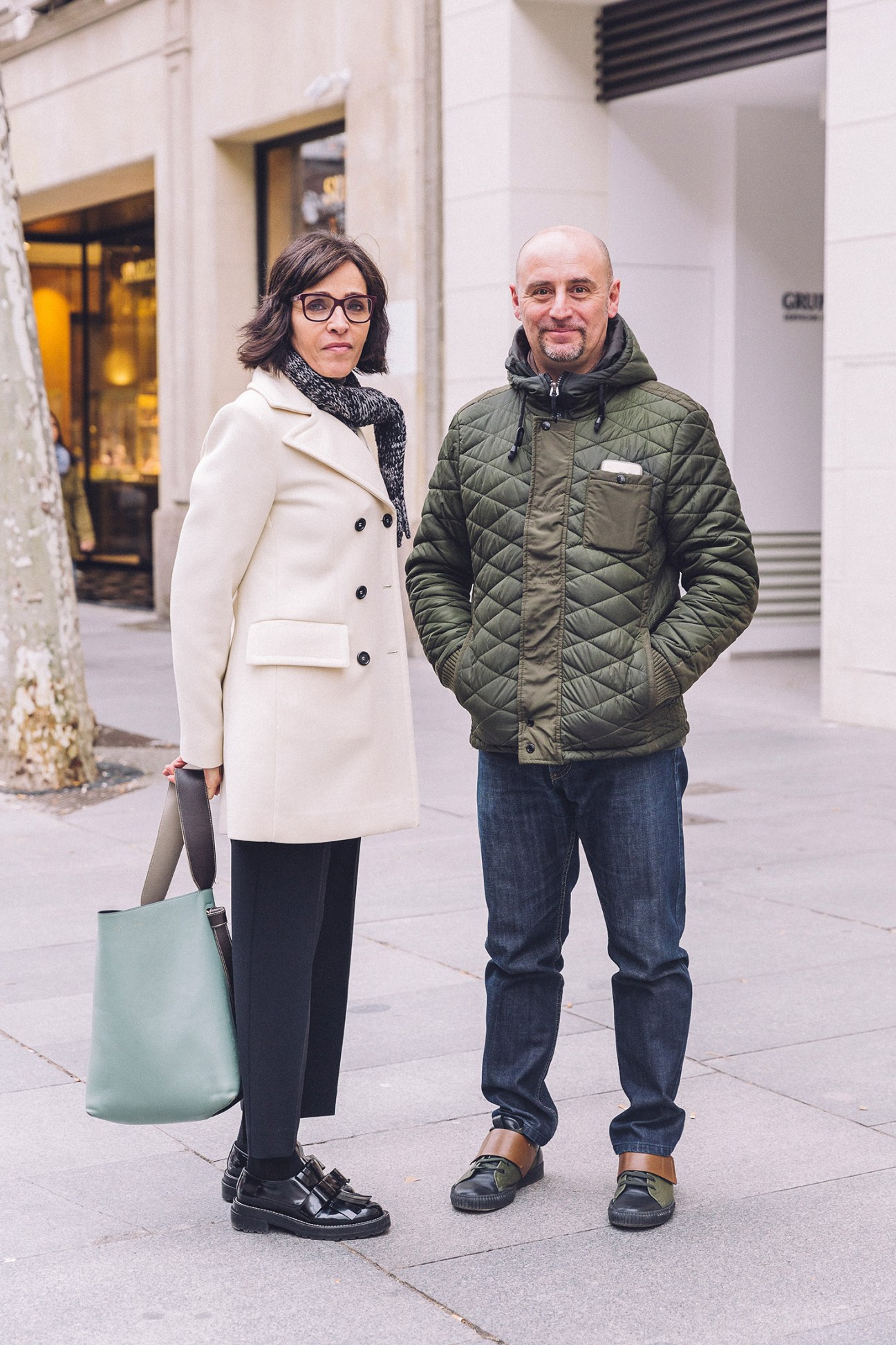 Man and woman standing on a Madrid street wearing casual winter clothing.