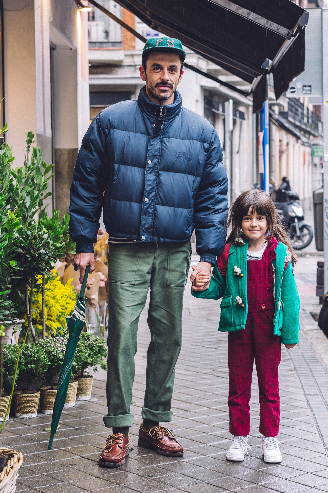 Man and young girl holding hands walking down a Madrid street