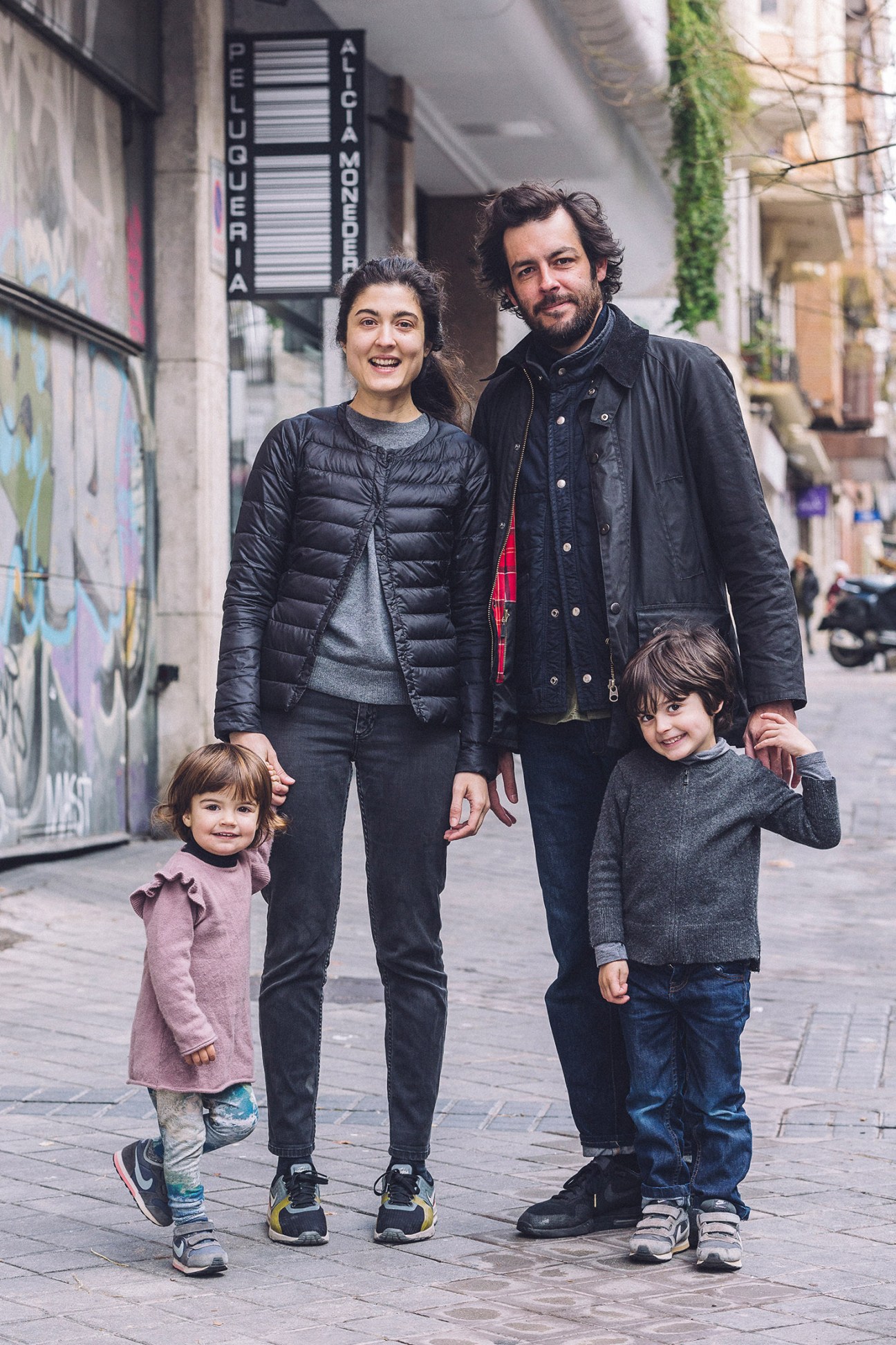 Family of four walking together on a Madrid street outside shops.