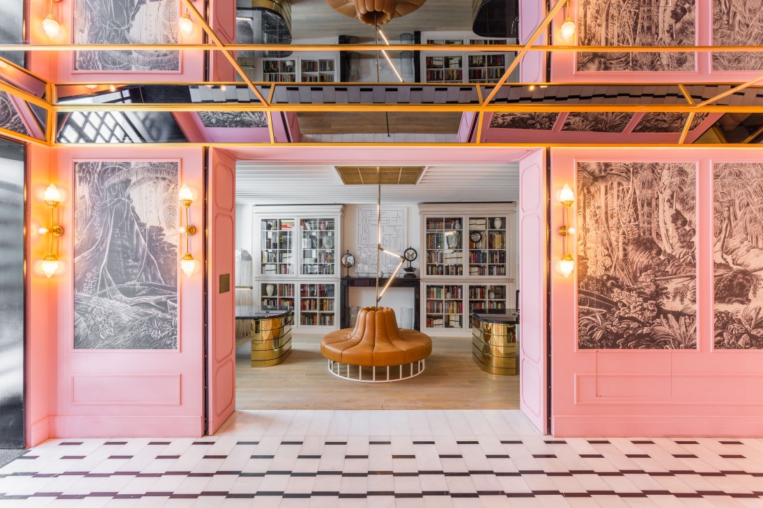 Sir Nikolai hotel's Study lounge with pink doors, velvet seating, bookshelves, and brass accents in Hamburg.