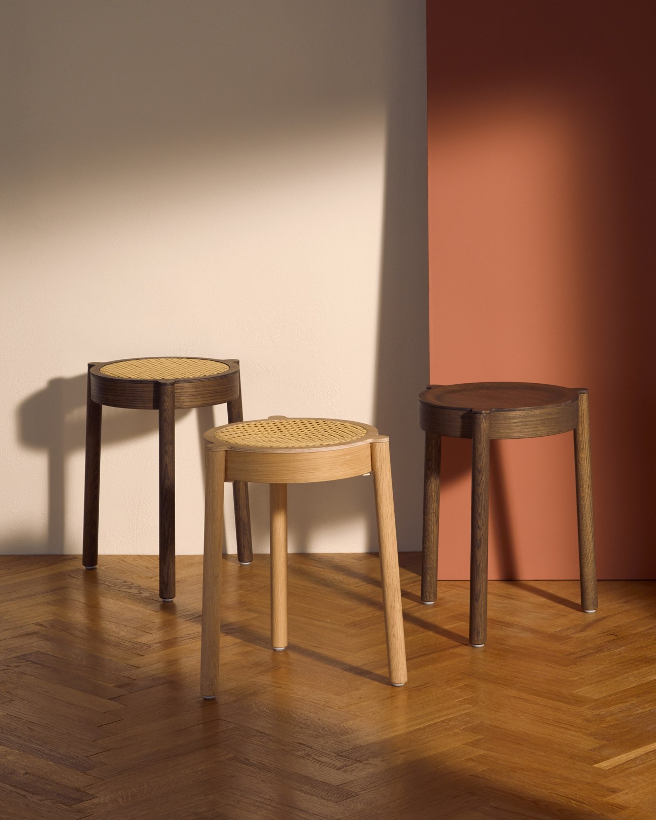 Three wooden Pal stools with woven cane mesh seats in natural light, showing design variations.