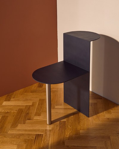 Piatto side table by Fucina with polished steel frame and circular black top on wooden floor.