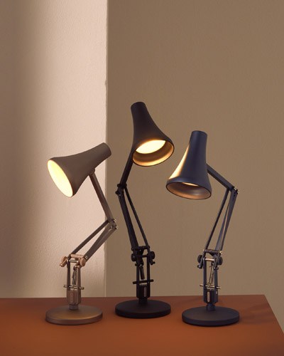 Three Anglepoise 90 Mini Mini desk lamps in black with adjustable arms and rotating shades, illuminated on a wooden surface.
