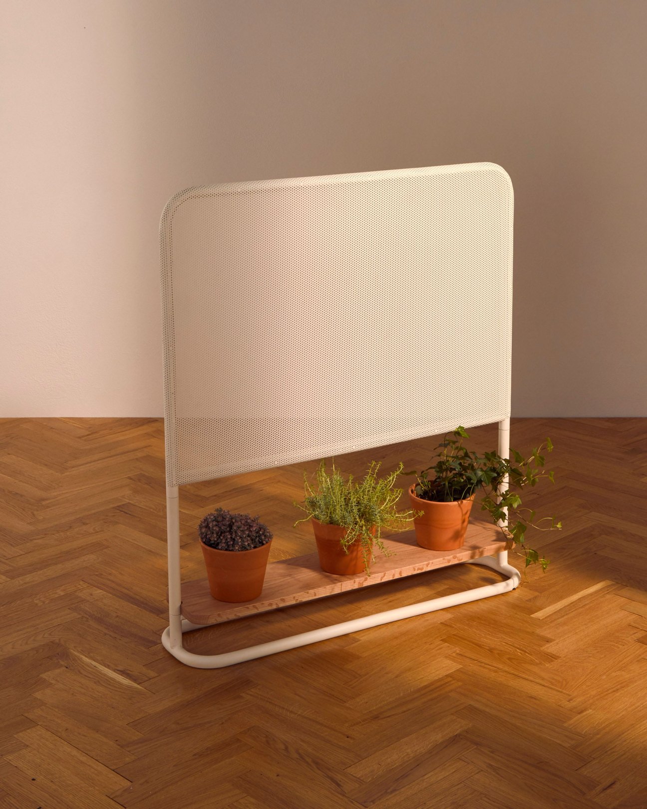Sasabe screen by Los Patrones with perforated metal panel and timber base displaying potted plants.