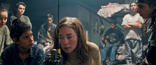 Scene from the film Monos showing young militia members in a dimly lit interior setting.